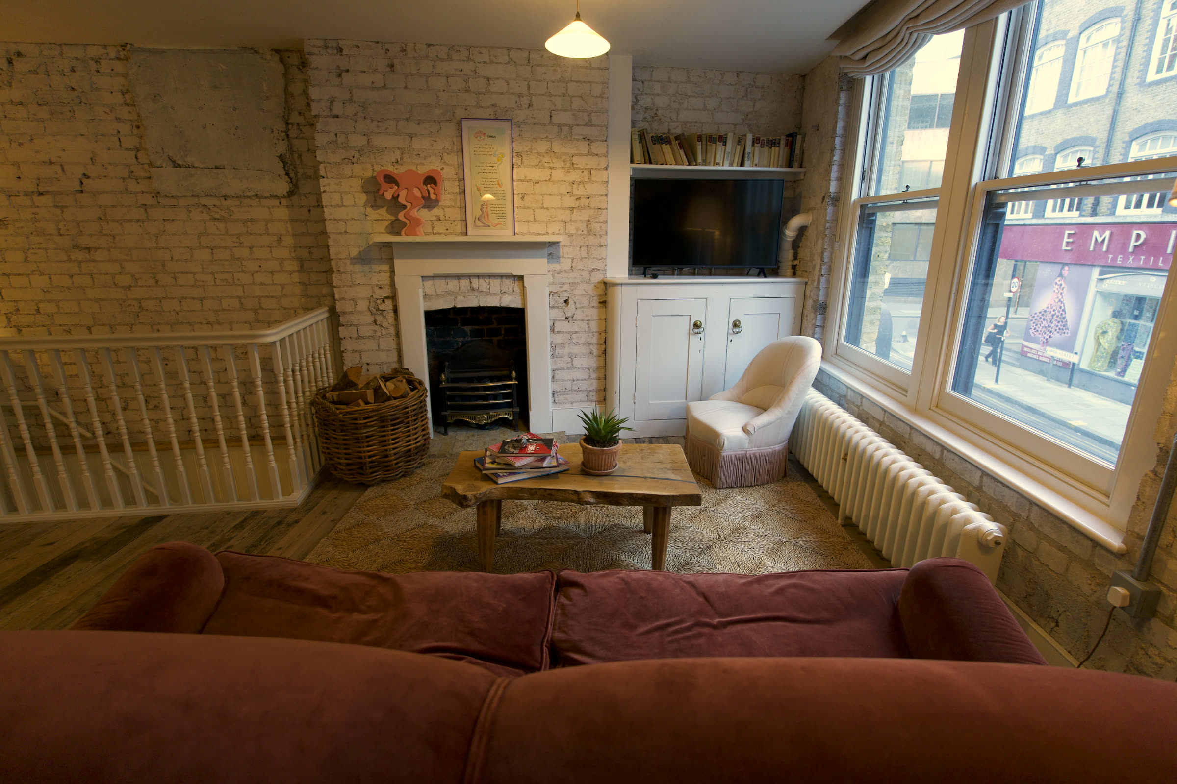 Living room with fireplace, log basket and velvet sofa