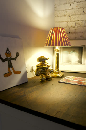 Gold lobster figurine on a sideboard beside a striped lamp
