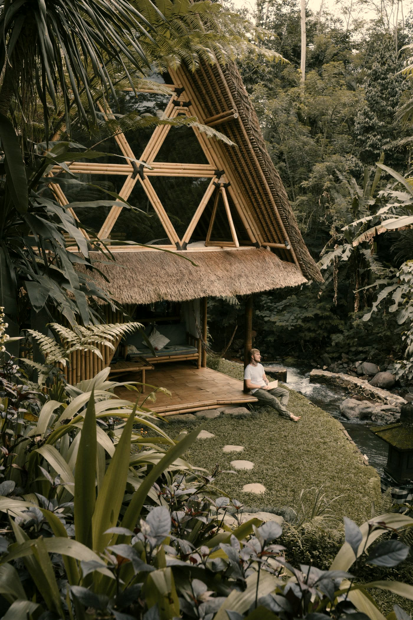 Bamboo hut set in dense jungle beside a quiet river