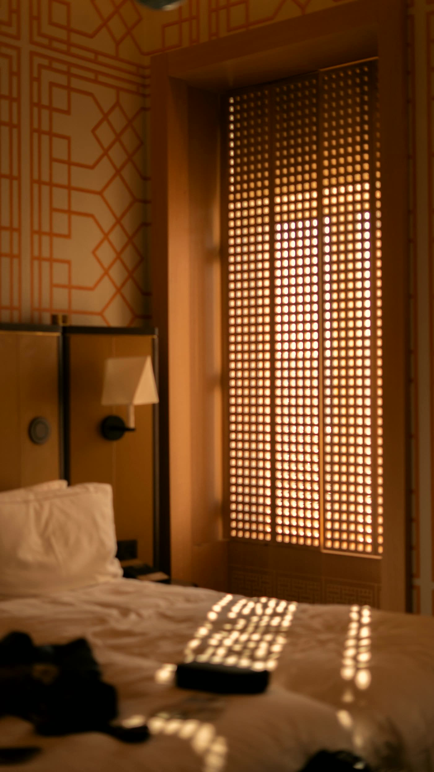 Bedroom with a latticed screen casting patterned light across the bed