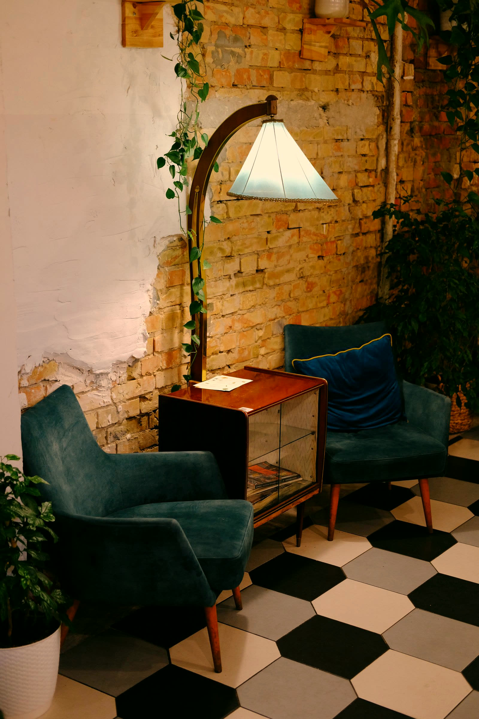 Vintage velvet armchairs and a brass lamp on exposed brick